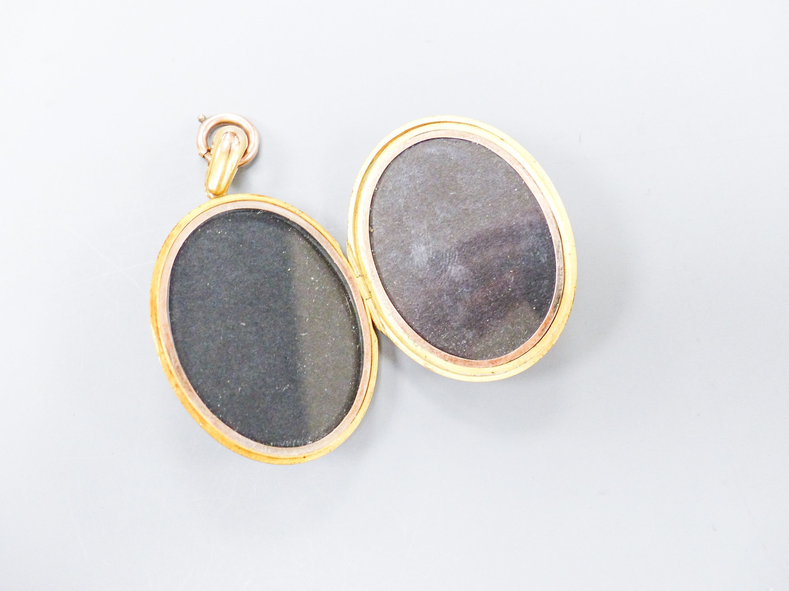 A Victorian engraved yellow metal oval locket, with engraved initials, 47mm, gross 31.6 grams, together with a small yellow metal and gem set pendant, 28mm, gross 1.5 grams.